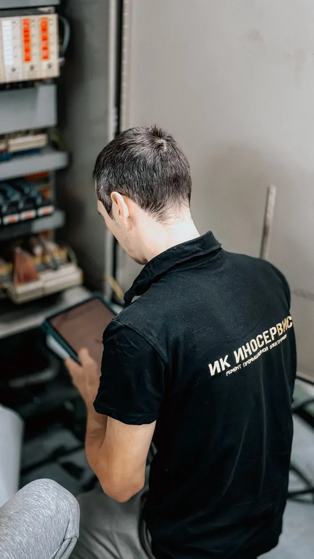 Stock photograph of an electrician inspecting a circuit panel indoors
